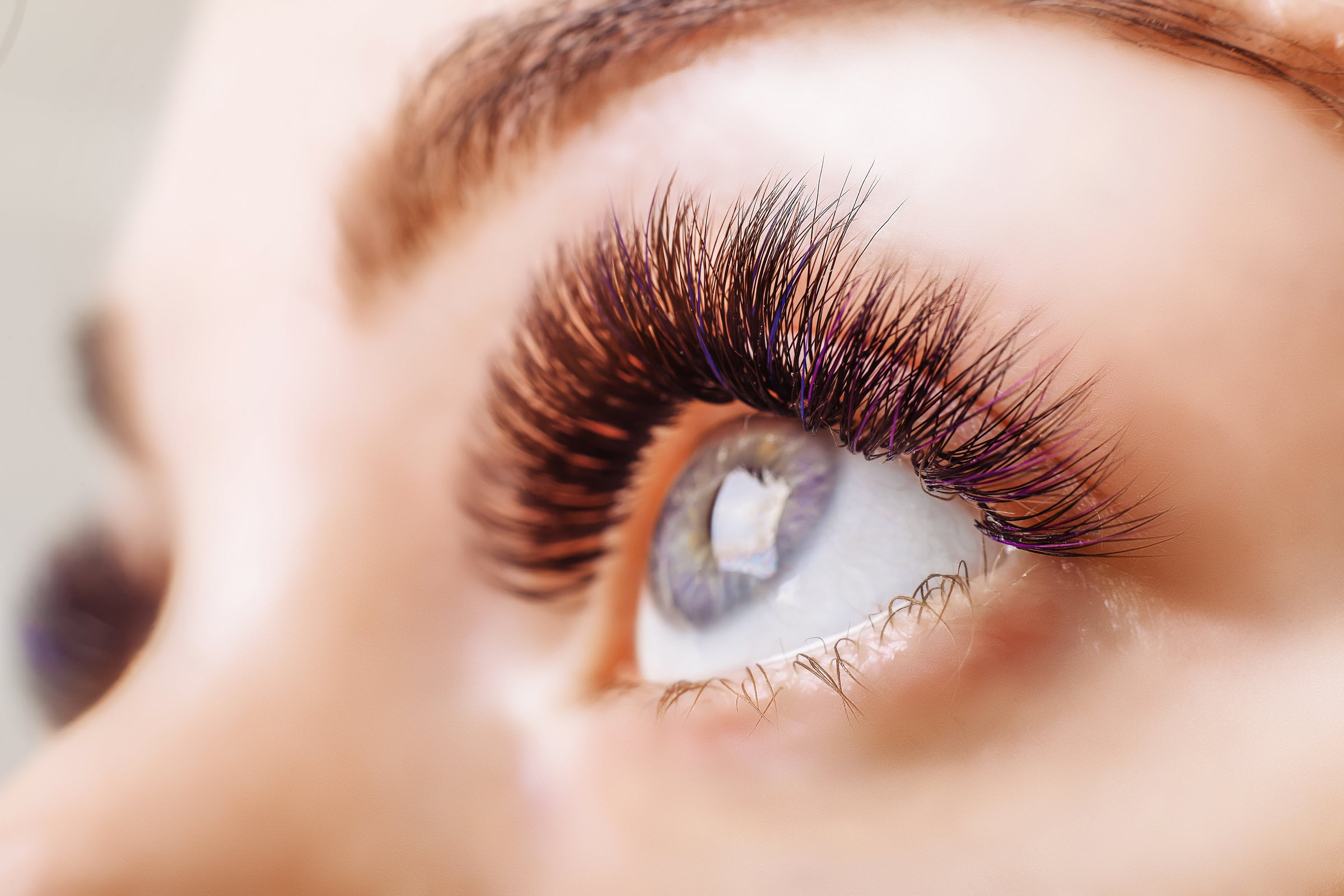 Woman with blue eyes and color eyelash extensions. Cartel Lash