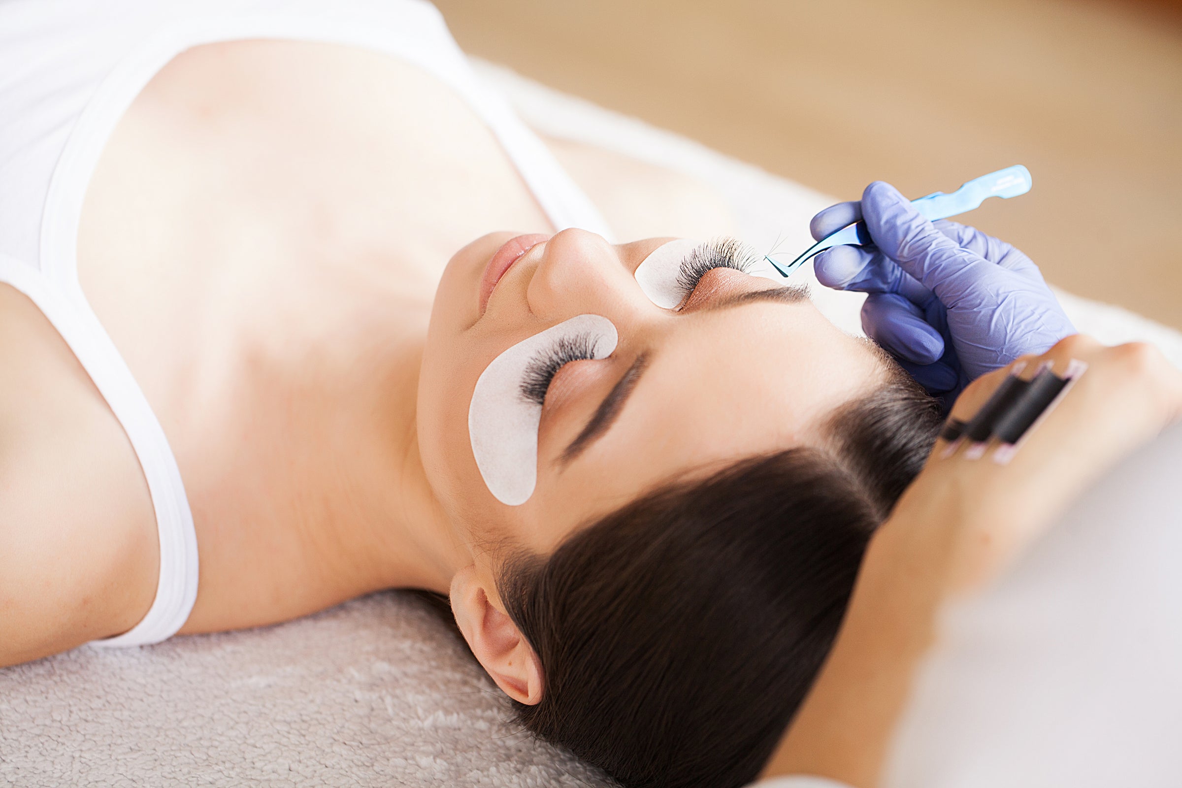 Woman getting lash extensions by lash technician. Cartel Lash