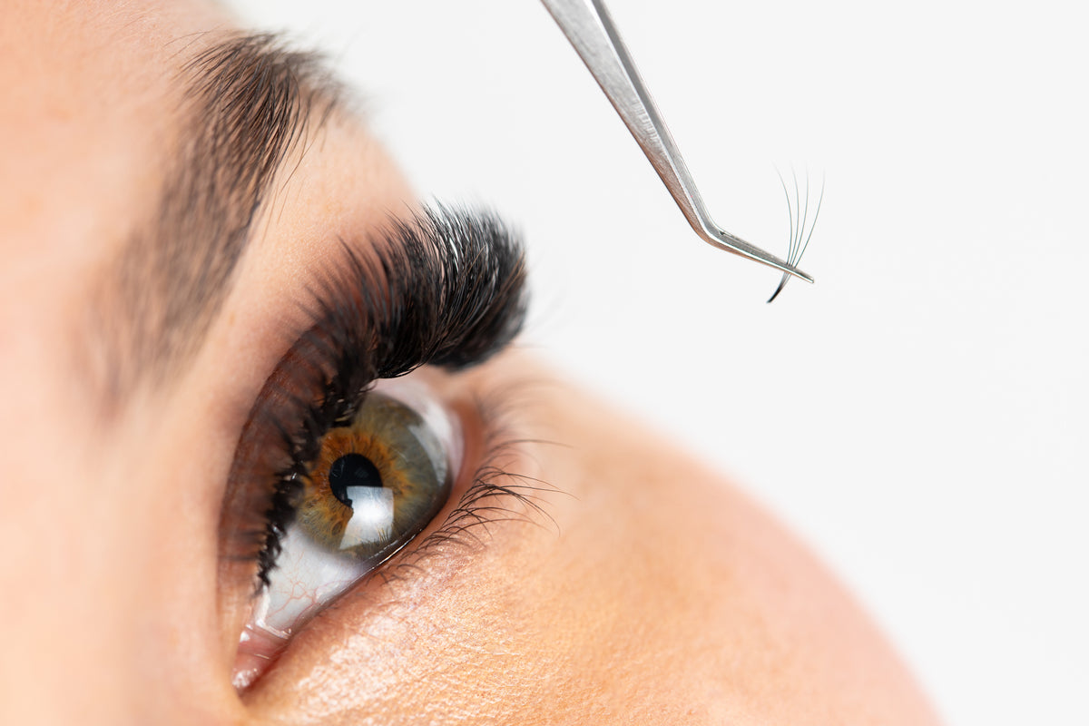 Eyelash glue on extension held by tweezers. Cartel Lash