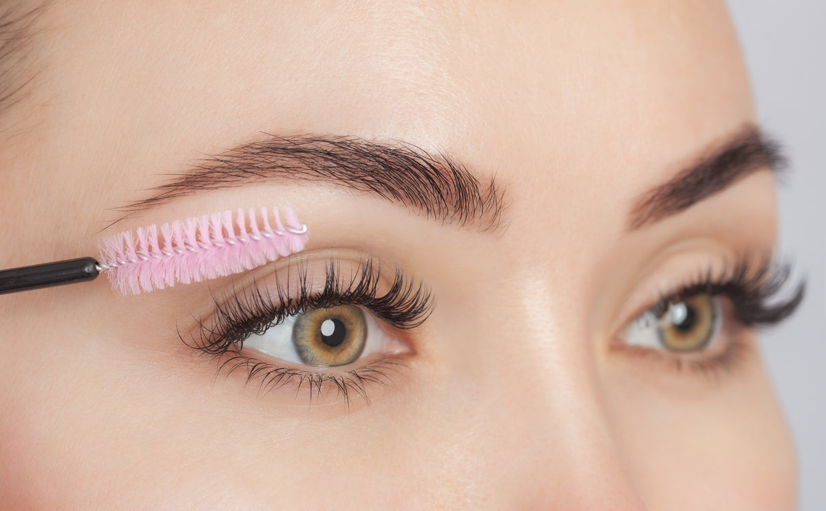 Woman brushing eyelash extensions with a lash brush. Cartel Lash