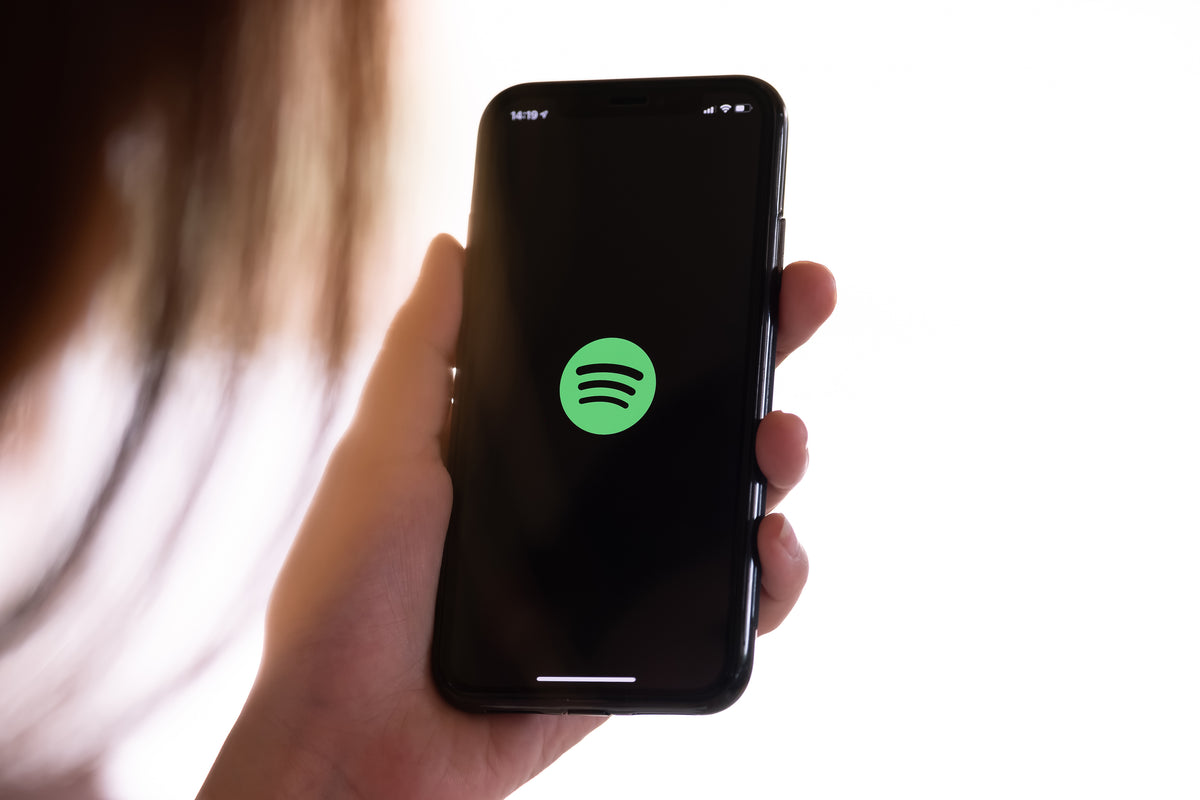Woman holding phone with Spotify logo