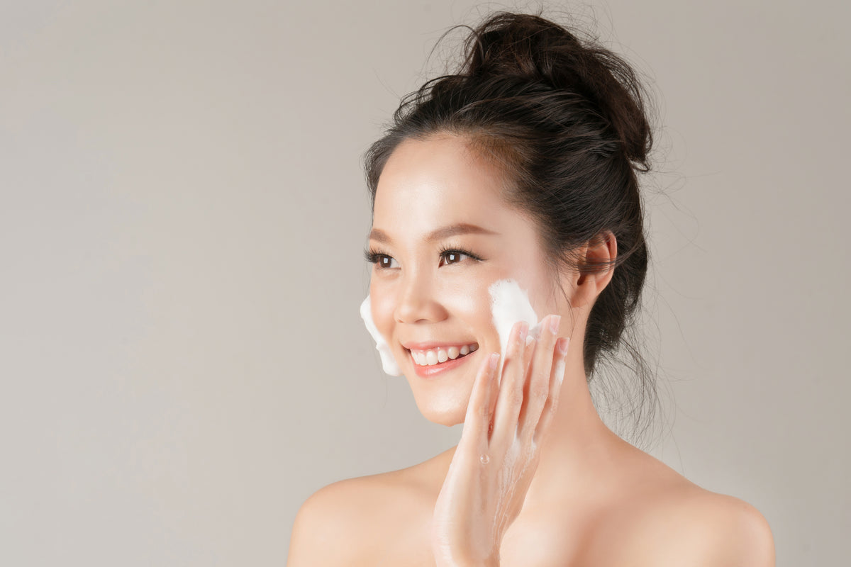 Woman with her hair tied puts foam on her cheeks to clean. Cartel Lash