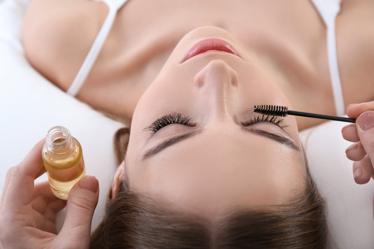 Oil on mascara wand being brushed on a woman's eyelash extensions. Cartel Lash