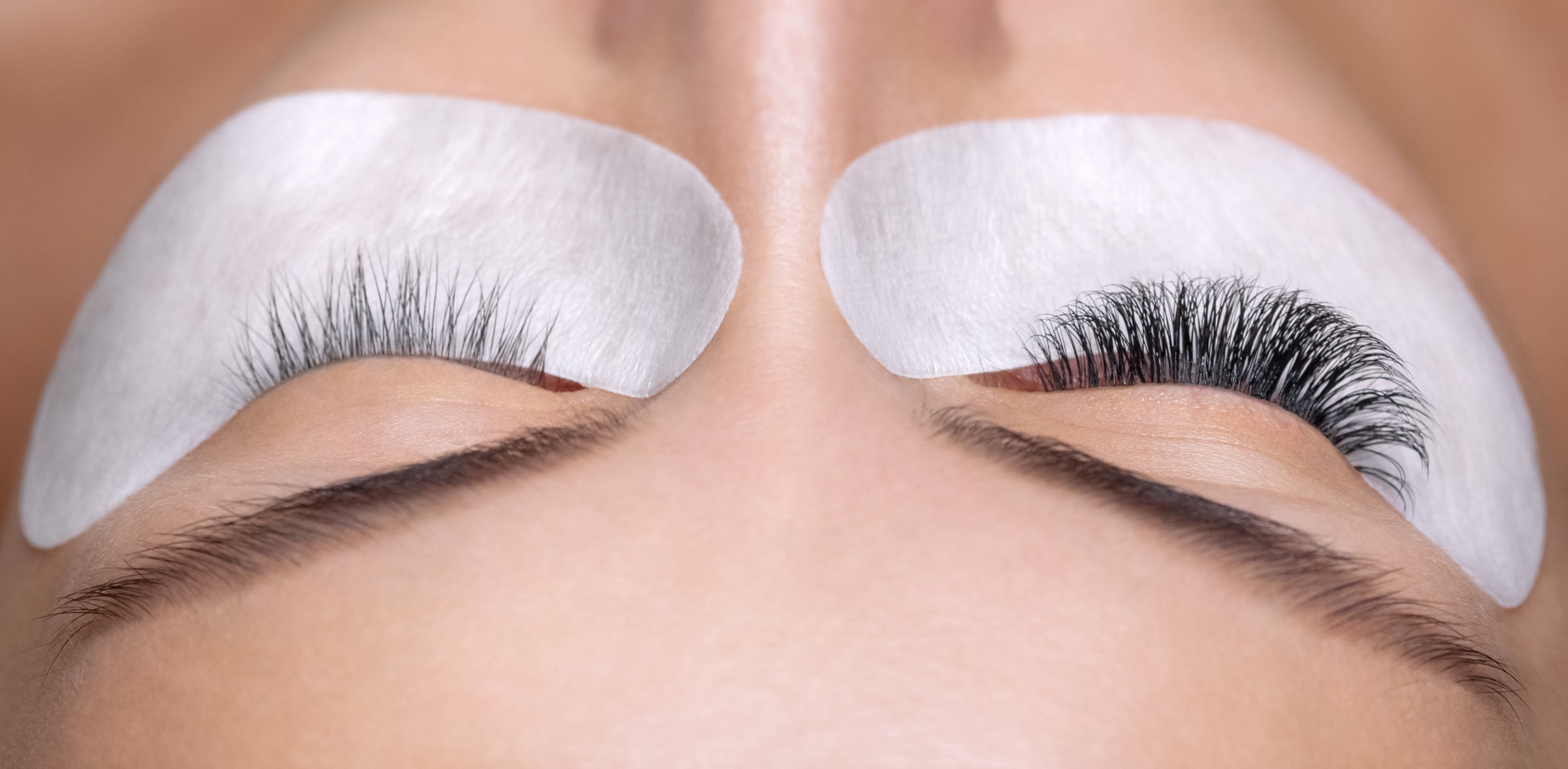 Woman with eyelash extensions on one eye with under eye gel pads. Cartel Lash