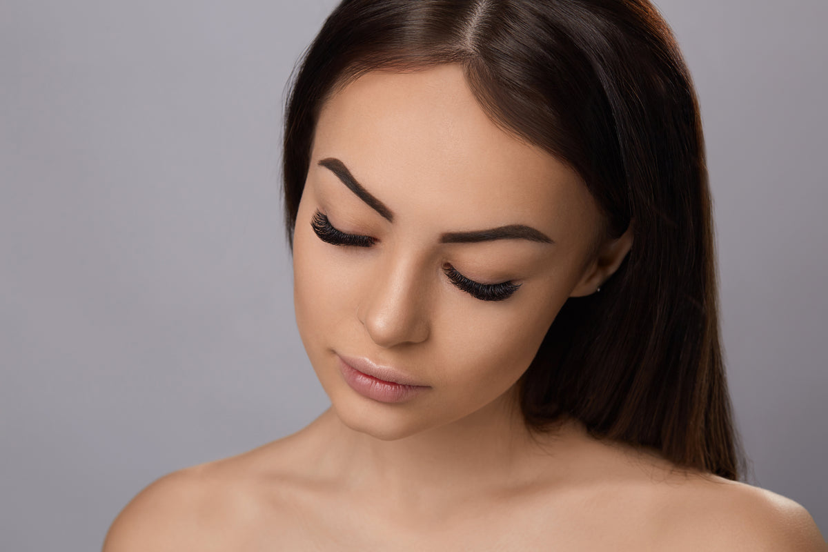 Closeup of woman looking down with a new set of lash extensions. Cartel Lash