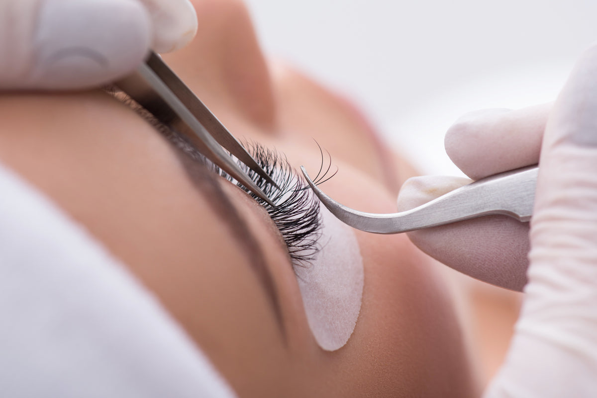 Lash tech applying individual lashes to a client during the lash extension process. Cartel Lash
