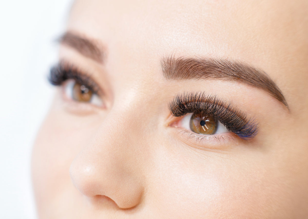 Woman with brown eyes showing her newly applied volume lash extensions. Cartel Lash
