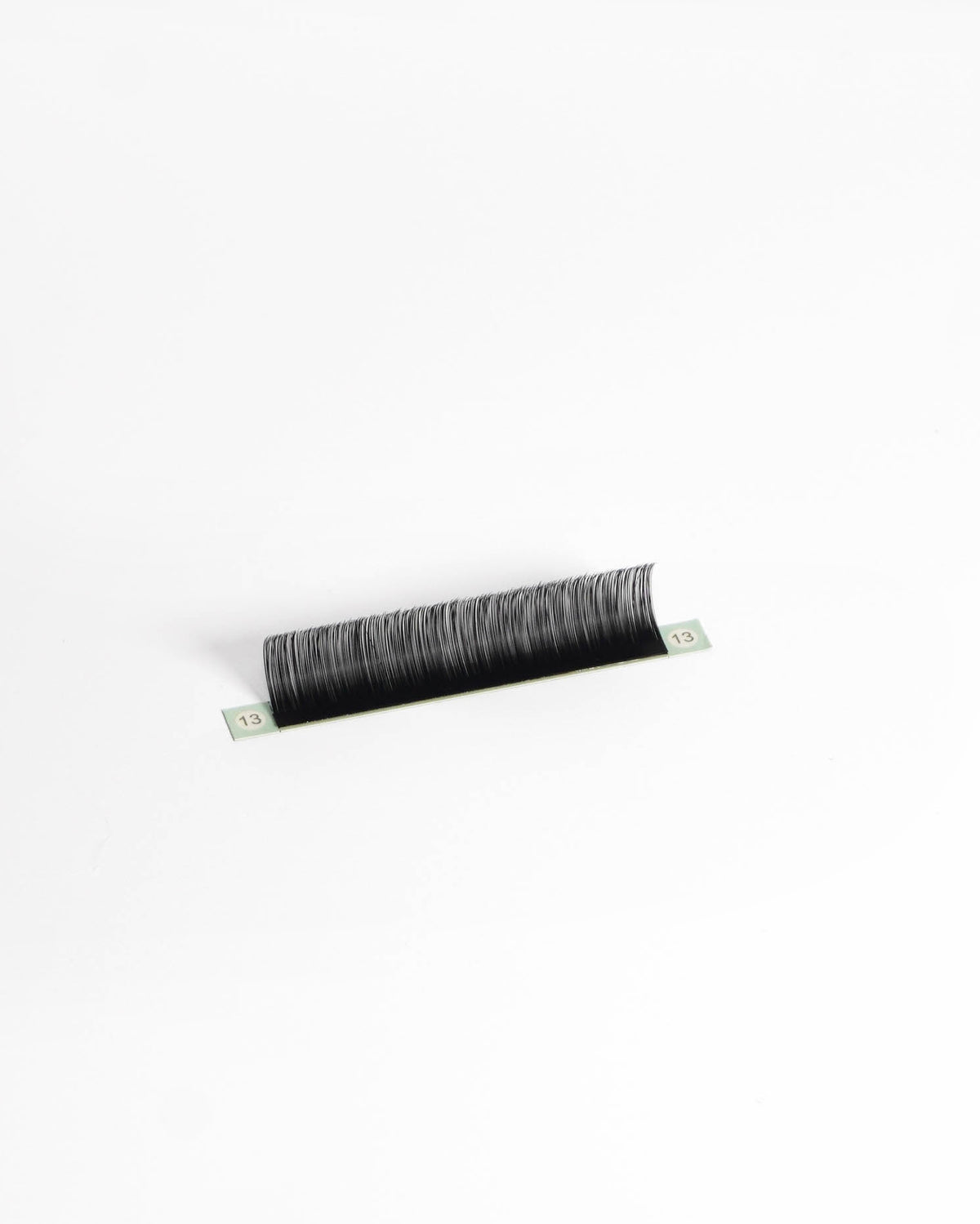 A single strip of black eyelash extensions or a lash strip, photographed on a clean white background.