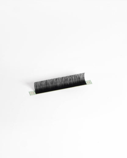 A single strip of black eyelash extensions or a lash strip, photographed on a clean white background.