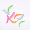 Six translucent silicone lash lift sheilds in pink, orange, green, and light blue, scattered on a plain white background.